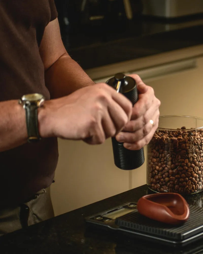 Mãos moendo café em um moedor manual